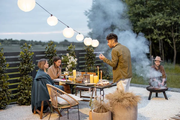 Amigos jantando no quintal à noite — Fotografia de Stock