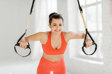 Sporcu kadın jimnastik salonunda askılarla sıkışıyor.