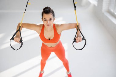TRX kayışlarında şınav çeken sporcu kadın