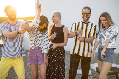 Genç şık arkadaşlar gün batımında çatıda kutlama yapıyorlar.