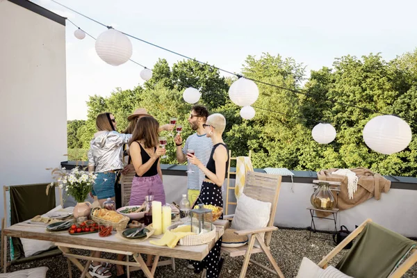 Молодые стильные друзья устраивают праздничный ужин на террасе на крыше — стоковое фото