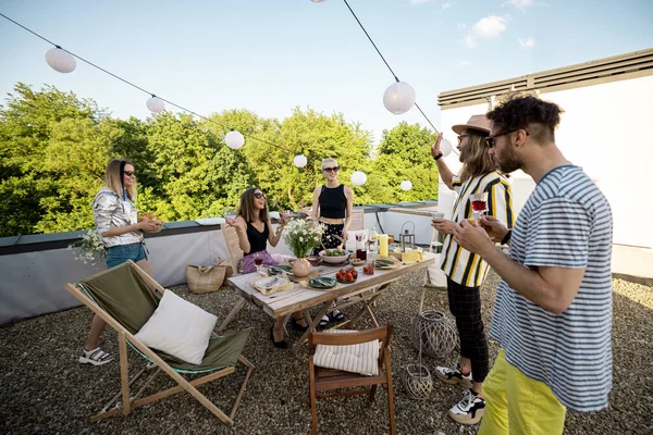 Amigos elegantes cenando en una terraza en la azotea — Foto de Stock