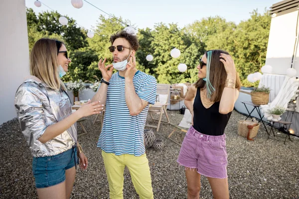 Vänner i ansiktsmasker samlas på en fest outdooors — Stockfoto