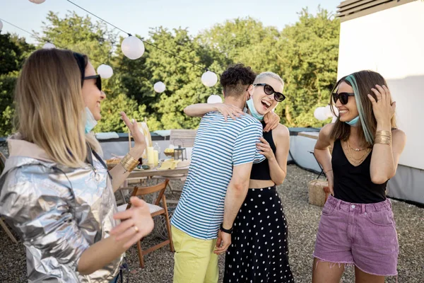 Amigos en máscaras faciales se reúnen en una fiesta al aire libre — Foto de Stock