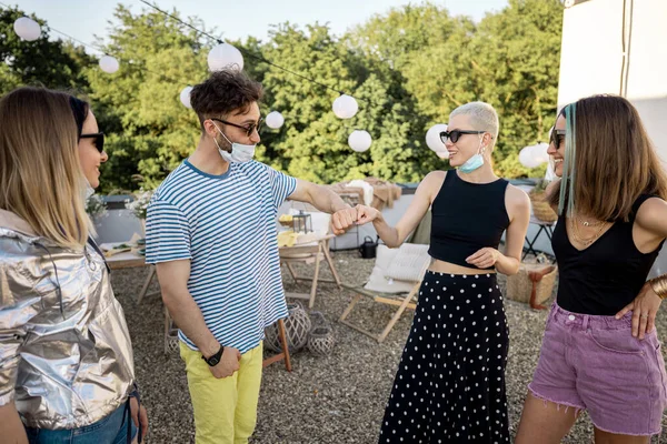 Vänner i ansiktsmasker samlas på en fest outdooors — Stockfoto