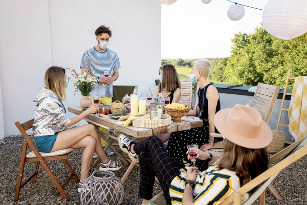 Vänner i ansiktsmasker har en festlig middag utomhus — Stockfoto