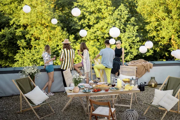 Jóvenes amigos elegantes que tienen una cena festiva en la terraza de la azotea — Foto de Stock