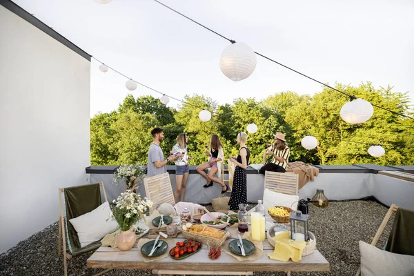 Νέοι στιλάτοι φίλοι έχουν ένα εορταστικό δείπνο στη βεράντα του τελευταίου ορόφου — Φωτογραφία Αρχείου