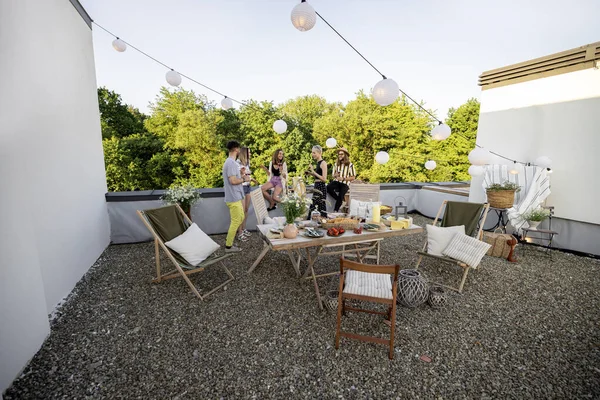 Jovens amigos elegantes tendo um jantar festivo no terraço do telhado — Fotografia de Stock