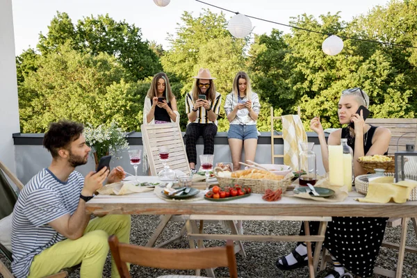 La gente pasa tiempo juntos, sentados por separado en teléfonos inteligentes en la fiesta al aire libre — Foto de Stock