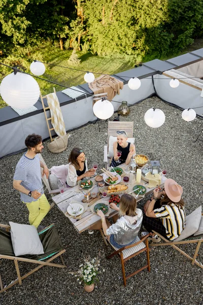 Os amigos têm um jantar festivo em um terraço no último piso — Fotografia de Stock