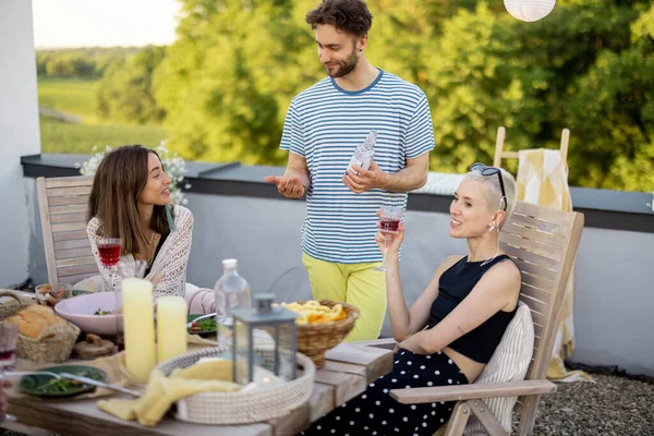 Jóvenes amigos elegantes que tienen una cena festiva en la terraza de la azotea —  Fotos de Stock