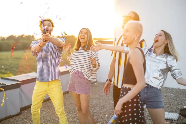 Jeunes amis élégants célébrant sur le toit au coucher du soleil — Photo