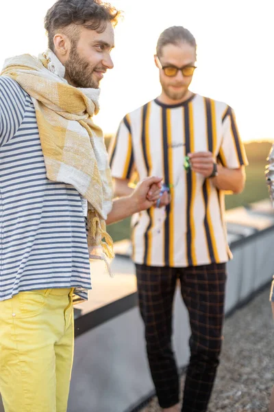 Young friends hang out at rooftop terrace on sunset