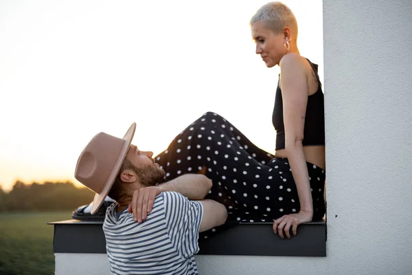 Jeune couple sur le toit au coucher du soleil — Photo