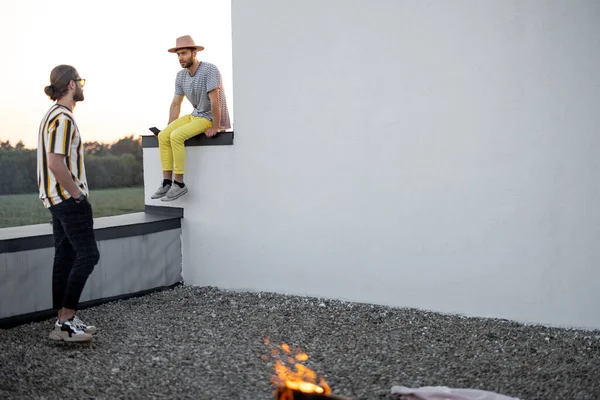 Deux amis masculins parlent sur le toit au coucher du soleil — Photo