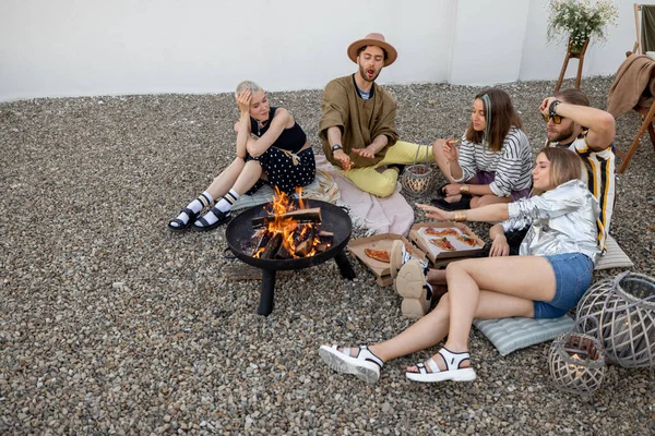 Friends sitting by the fireplace outdoors — Stock Photo, Image