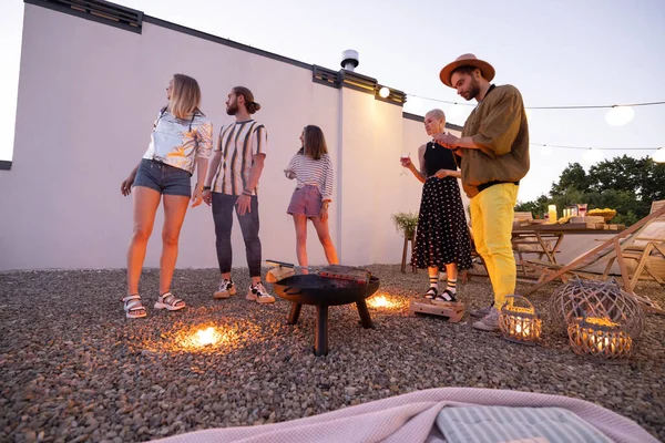 Vänner vid en öppen spis på taket vid solnedgången — Stockfoto