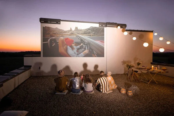Folk ser film på takterrassen ved solnedgang. – stockfoto
