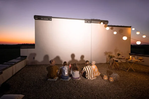 Les gens qui regardent un film sur le toit-terrasse au coucher du soleil — Photo