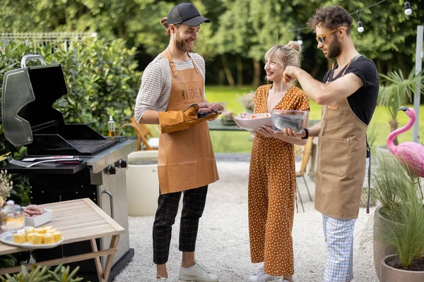 Amis cuisson des aliments sur un gril à l'extérieur — Photo