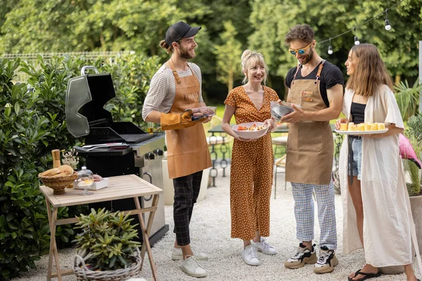 Amigos cozinhar comida em uma grelha ao ar livre — Fotografia de Stock