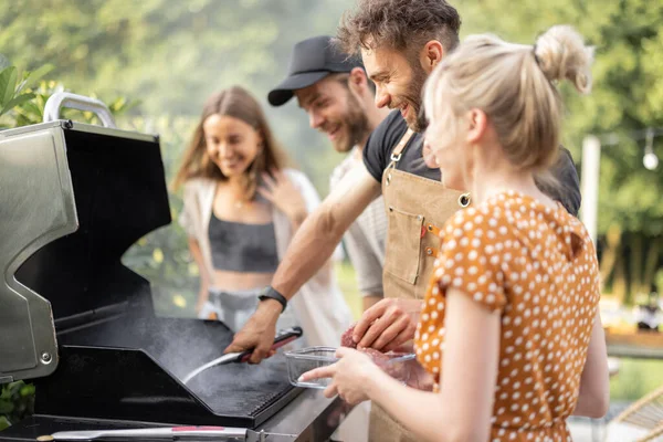 Gebeurt vrienden koken op een grill in de achtertuin — Stockfoto