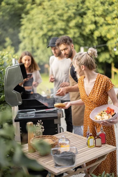 Gebeurt vrienden koken op een grill in de achtertuin — Stockfoto