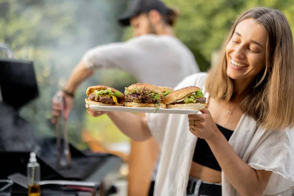 Amigos haciendo hamburguesas en un picnic — Foto de Stock