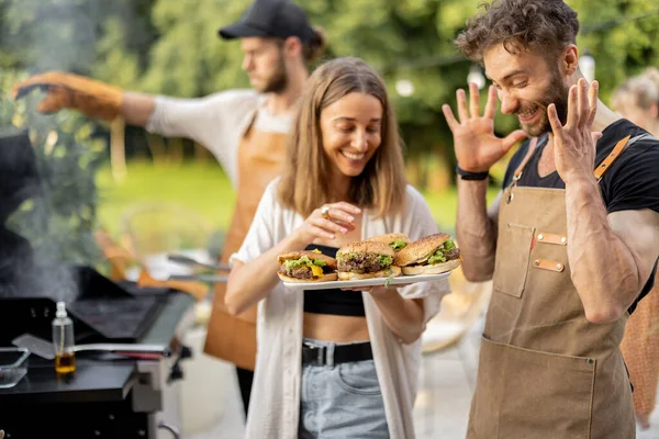 Vänner njuter av hamburgare på picknick — Stockfoto