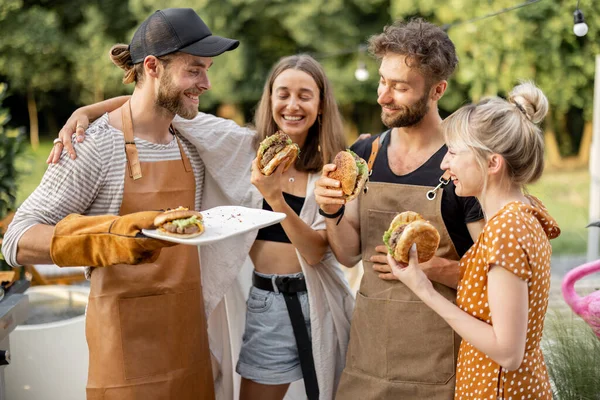 Vänner njuter av hamburgare på picknick — Stockfoto