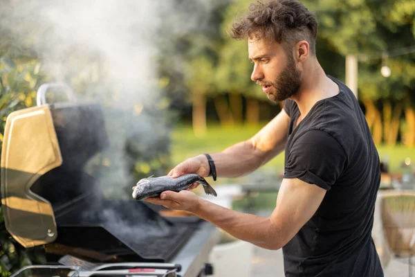 Man koken van vis en groenten op een grill buiten — Stockfoto