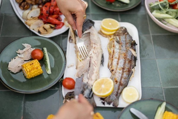 Eating grilled fish and vegetables, close-up — Stock Photo, Image