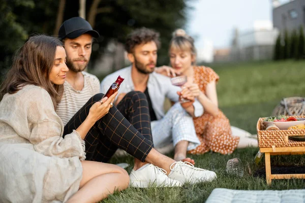Vänner sitter tillsammans med alkohol på picknick — Stockfoto