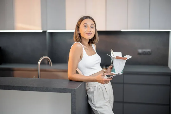 Жінка з їжею і телефоном на кухні — стокове фото