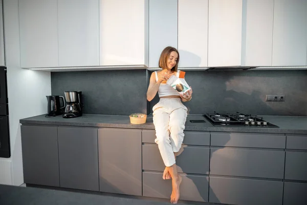 Kvinnan äter hämtmat i modernt kök — Stockfoto