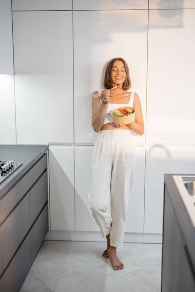 Relaxed woman eating asian takeaway food on the modern kitchen