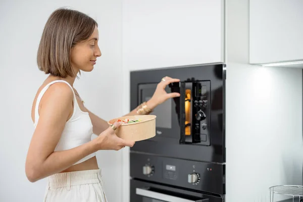 Mulher aquecimento de alimentos com máquina de microondas — Fotografia de Stock