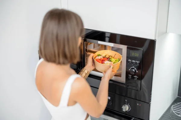 Mulher aquecimento de alimentos com máquina de microondas — Fotografia de Stock