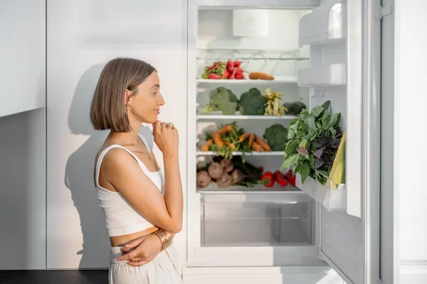 Mulher com legumes saudáveis na geladeira — Fotografia de Stock