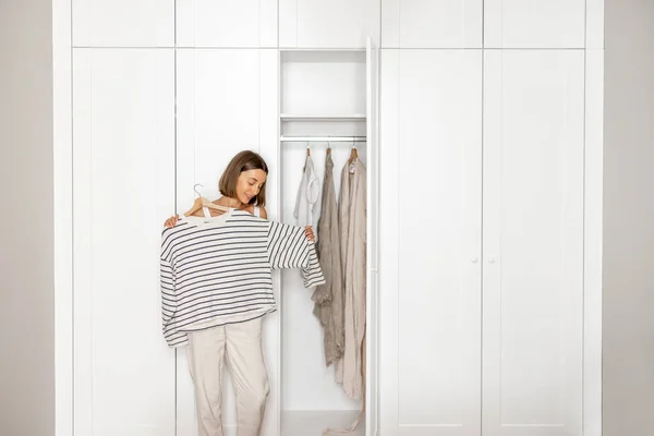 Jeune femme choisit ce qu'il faut porter près du placard — Photo