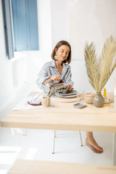 Kvinne som spiser frokost i moderne leilighet – stockfoto