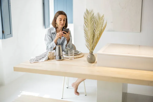 Kvinna med mobiltelefon hemma — Stockfoto