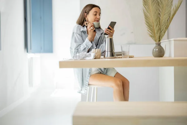 Kvinna med mobiltelefon hemma — Stockfoto