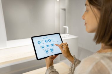 Kadın mobil cihazlarla akıllı mutfak aletlerini kontrol ediyor