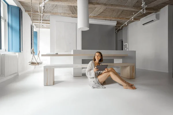Kvinna arbetar på en digital surfplatta medan du sitter avslappnad på modern lägenhet — Stockfoto