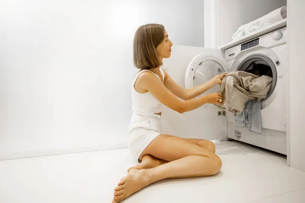 Frau wäscht Kleidung mit Waschmaschine im Badezimmer — Stockfoto