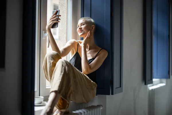 一个时髦的女人在窗前打电话 — 图库照片