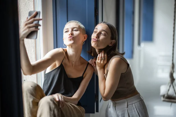 Twee vrouwen hebben plezier, praten online op mobiele telefoon door het raam — Stockfoto