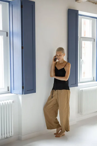 Donna con telefono vicino alla finestra a casa — Foto Stock